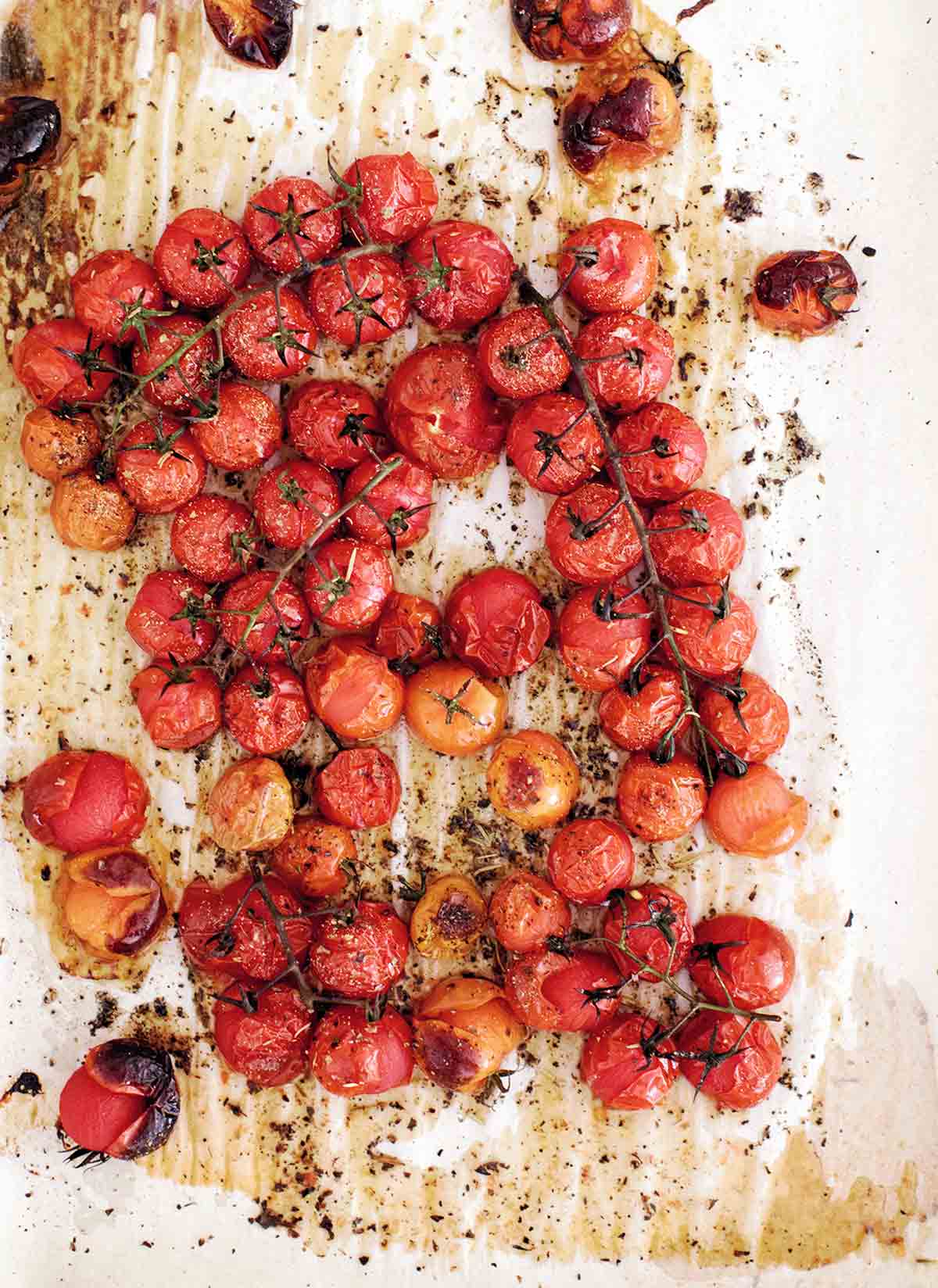 Bunches of roasted cherry tomatoes on a piece of parchment.
