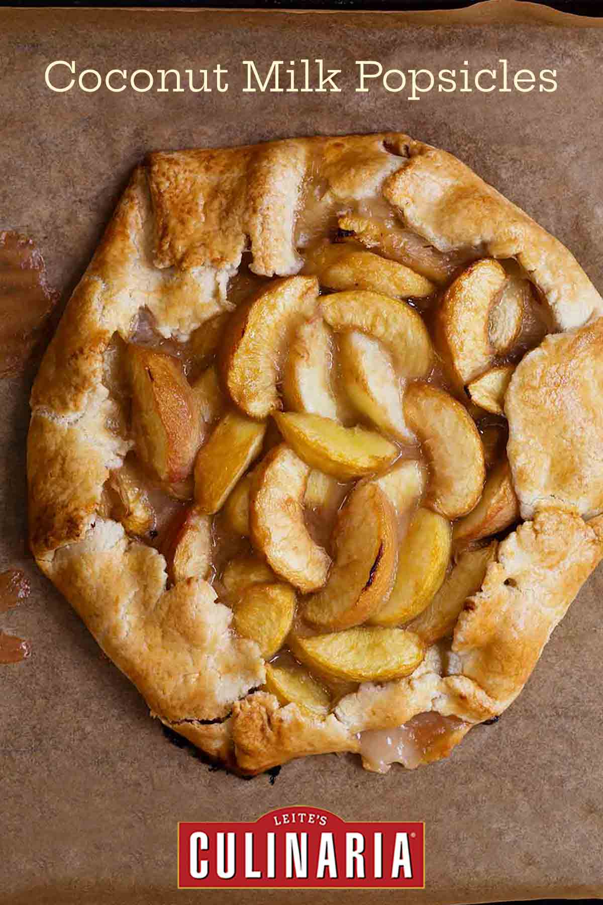A white peach crostata--slices of white peaches in a circle of dough folded over on the edges sitting a sheet of parchment.