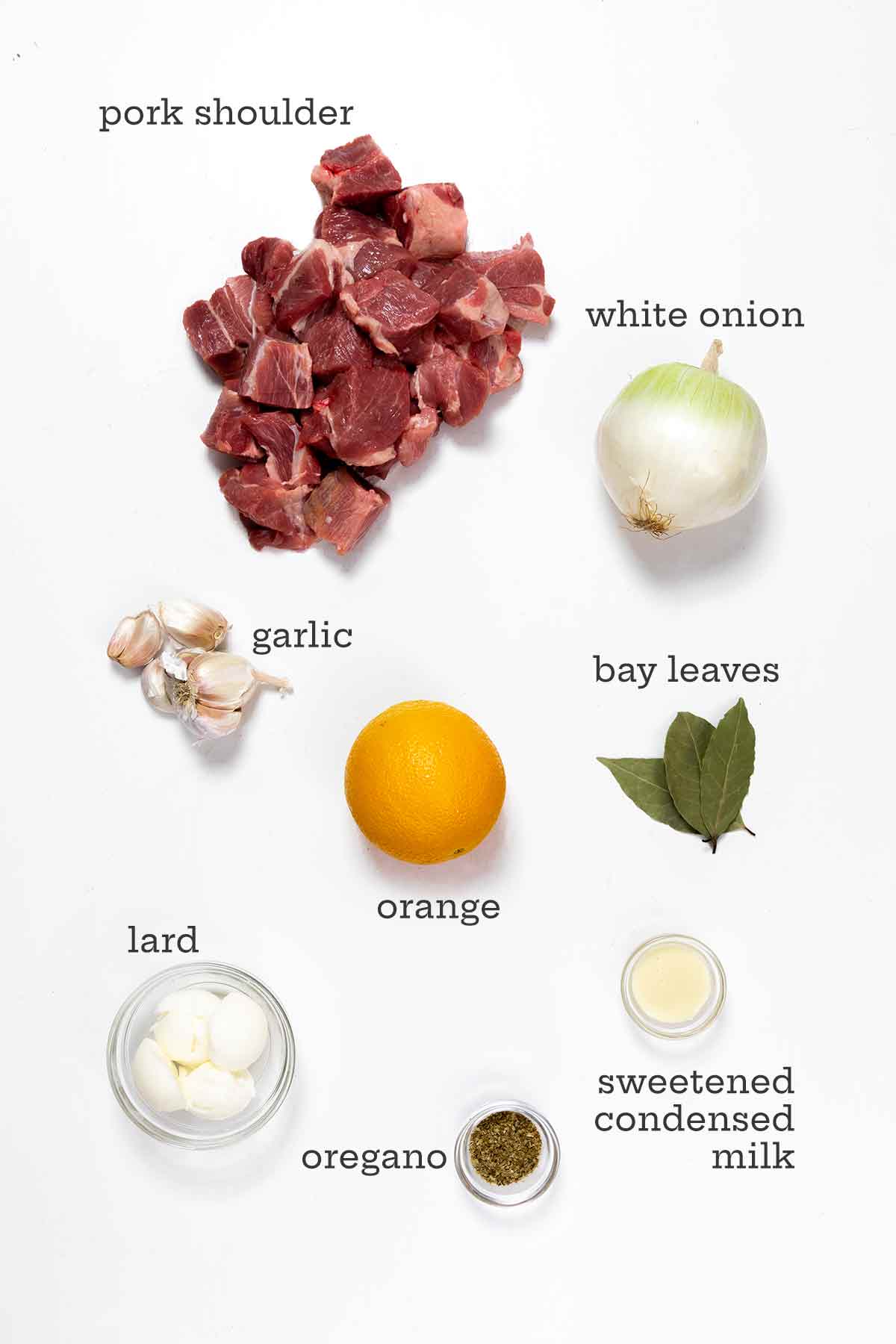 Ingredients for carnitas--pork shoulder, onion, garlic, oranges, bay leaves, lard, oregano, and sweetened condensed milk.