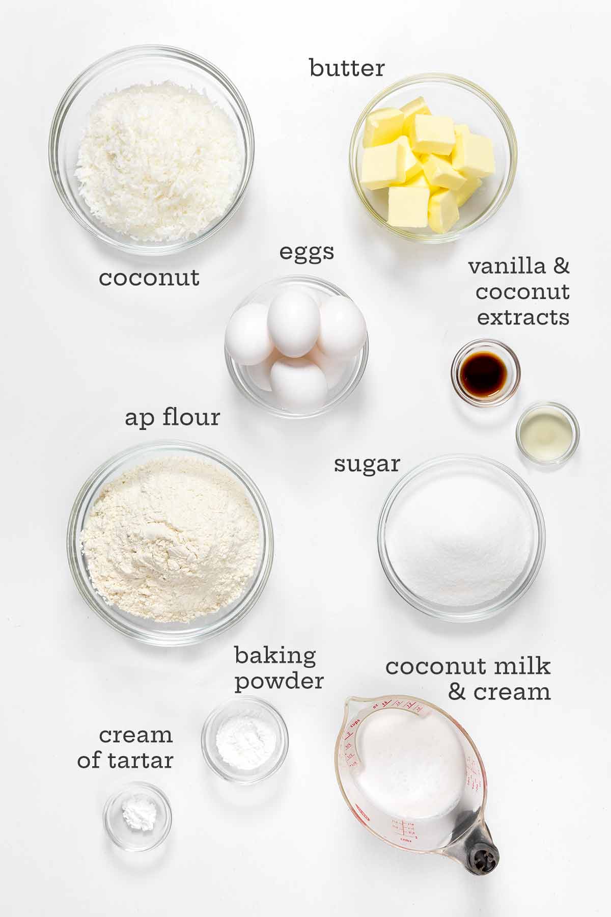 The ingredients for old-fashioned coconut cake, including bowls of coconut, butter, flour, sugar, coconut milk, and coconut cream.