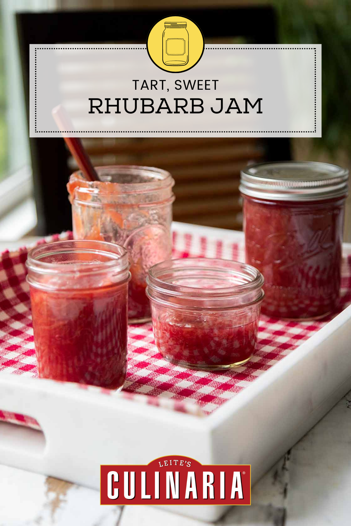 Four jars of rhubarb jam on a white tray lined with checkered cloth.