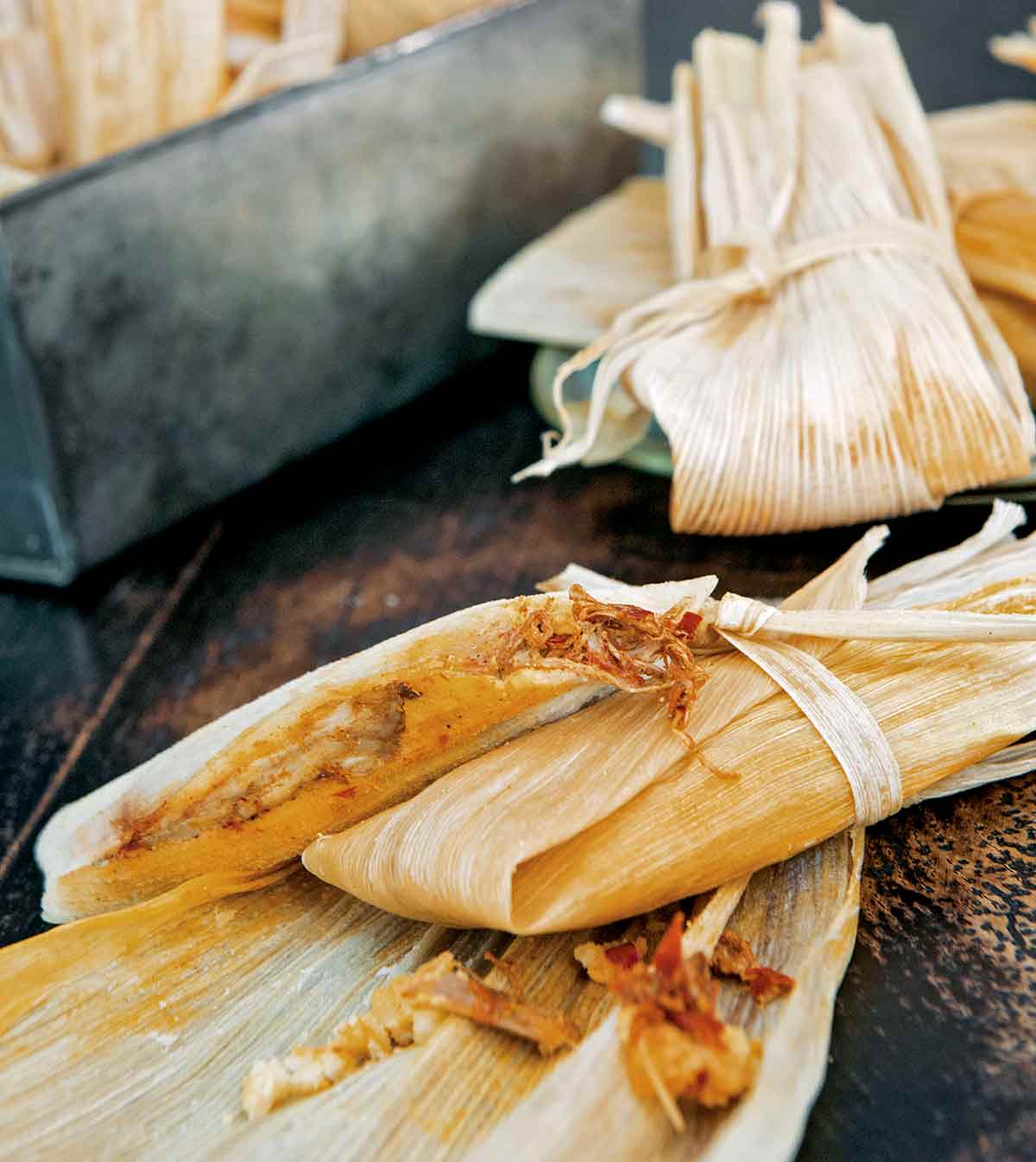 Several tamales on a wooden table.