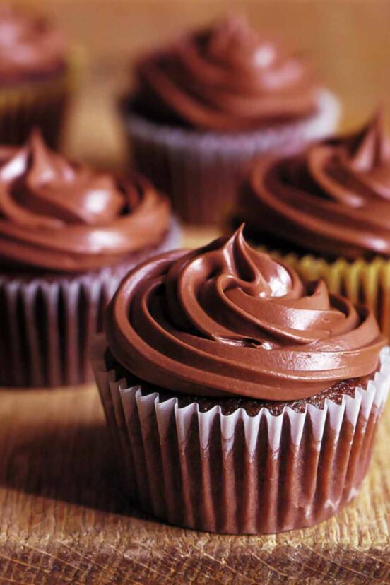 Four chocolate cupcakes topped with chocolate frosting.