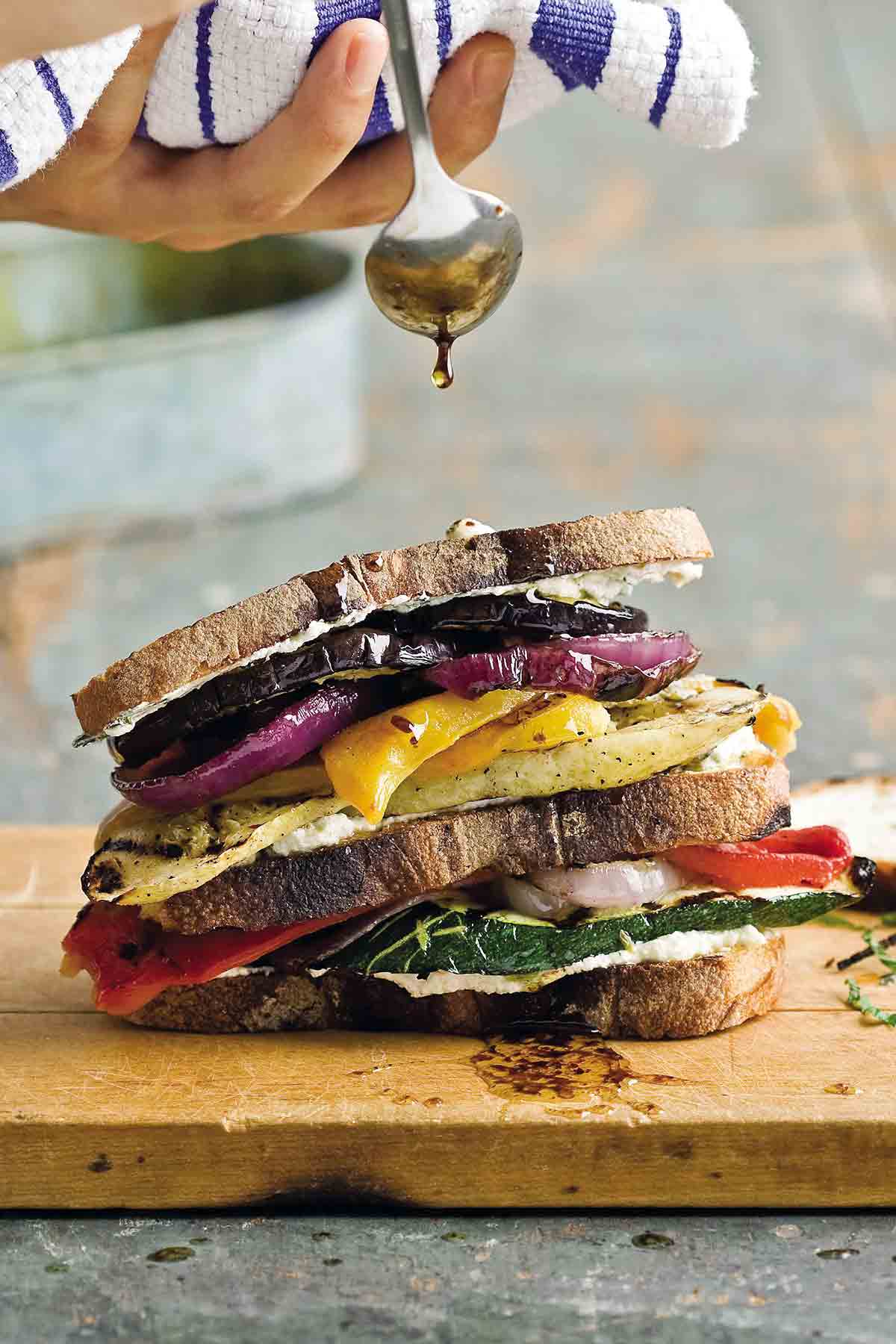 A grilled vegetable sandwich on a wooden cutting board.