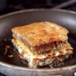 A cheese crusted grilled cheese sandwich in a skillet.