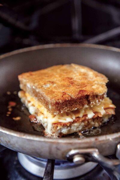 A cheese crusted grilled cheese sandwich in a skillet.