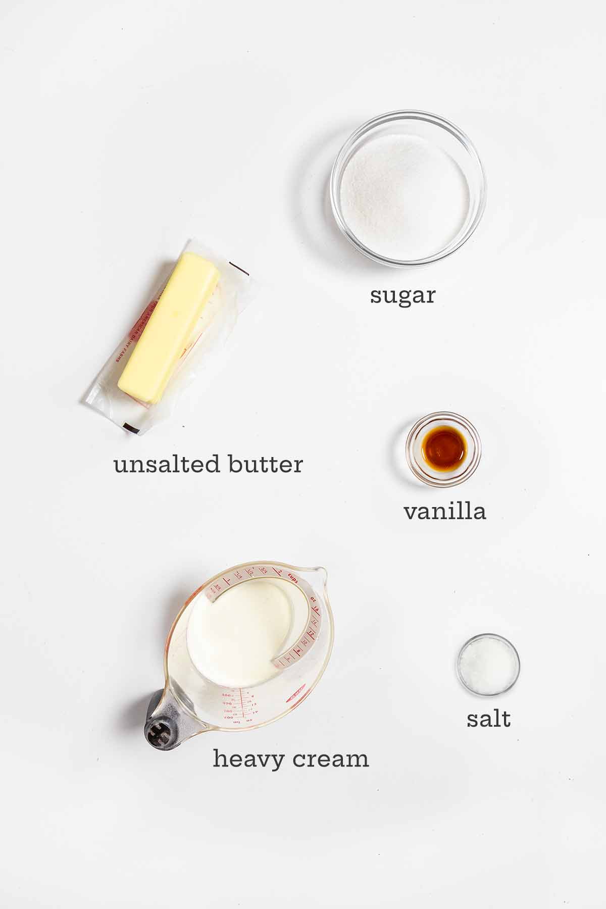 Ingredients for homemade caramel sauce--butter, sugar, vanilla, heavy cream, and salt.