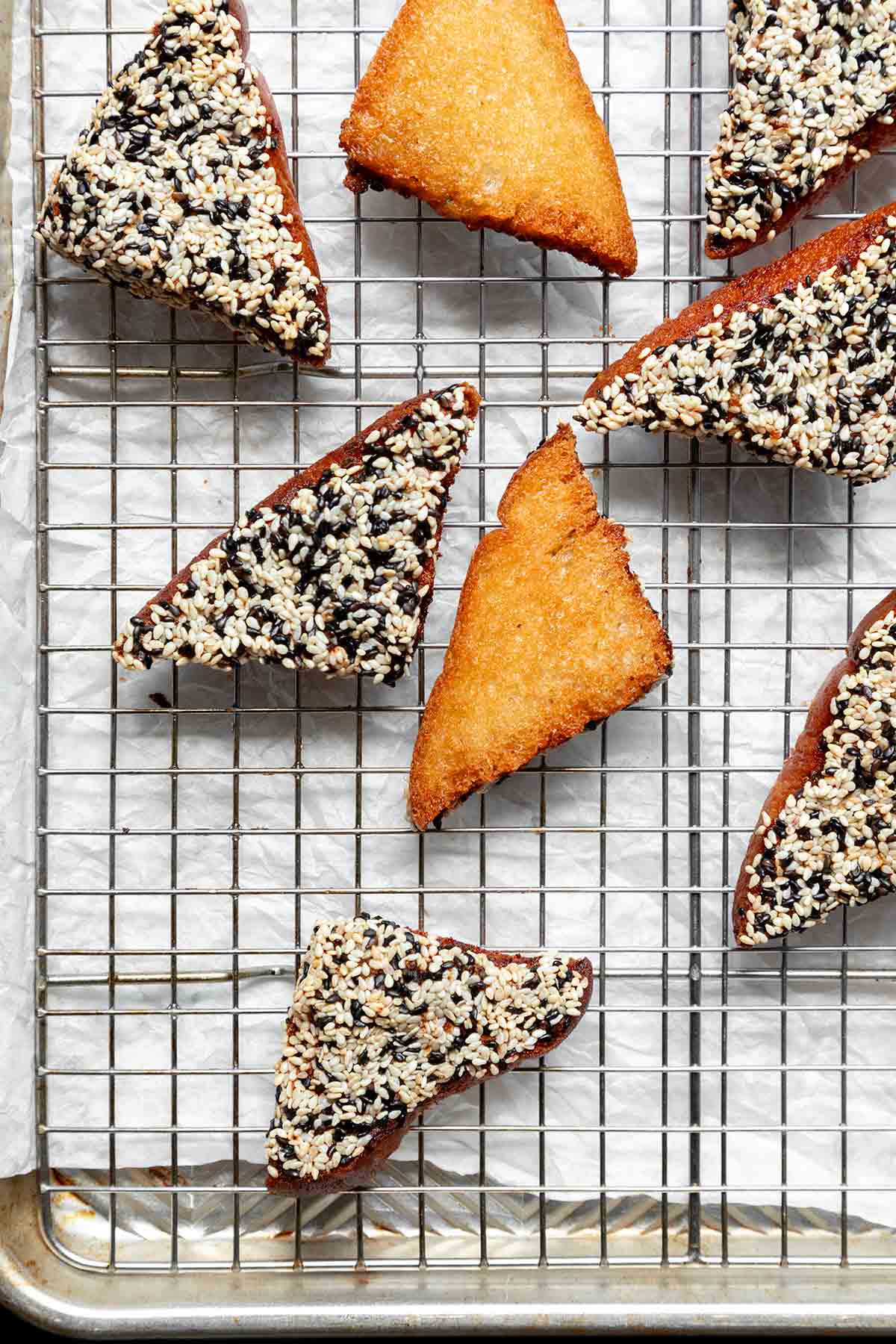 Triangles of fried shrimp toast cooling on a wire rack.