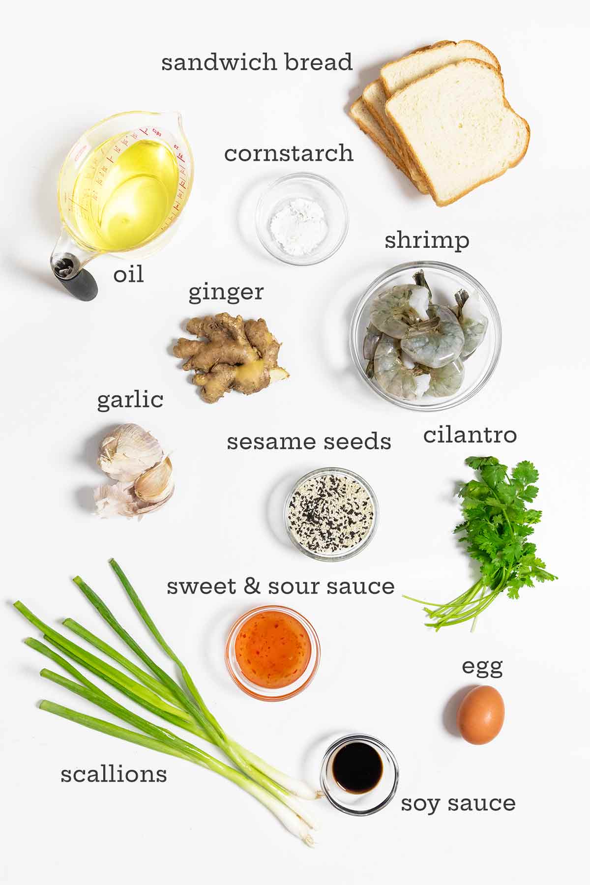 Ingredients for shrimp toast--bread, oil, cornstarch, shrimp, ginger, garlic, sesame seeds, cilantro, scallions, egg, soy sauce, and sweet and sour sauce.