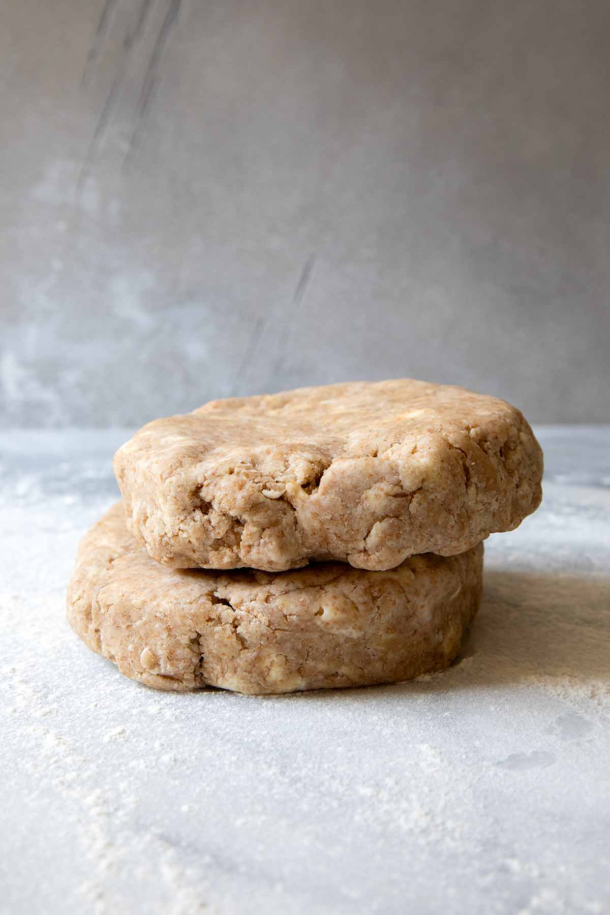 Two disks of whole wheat pie crust dough stacked one on top of the other.