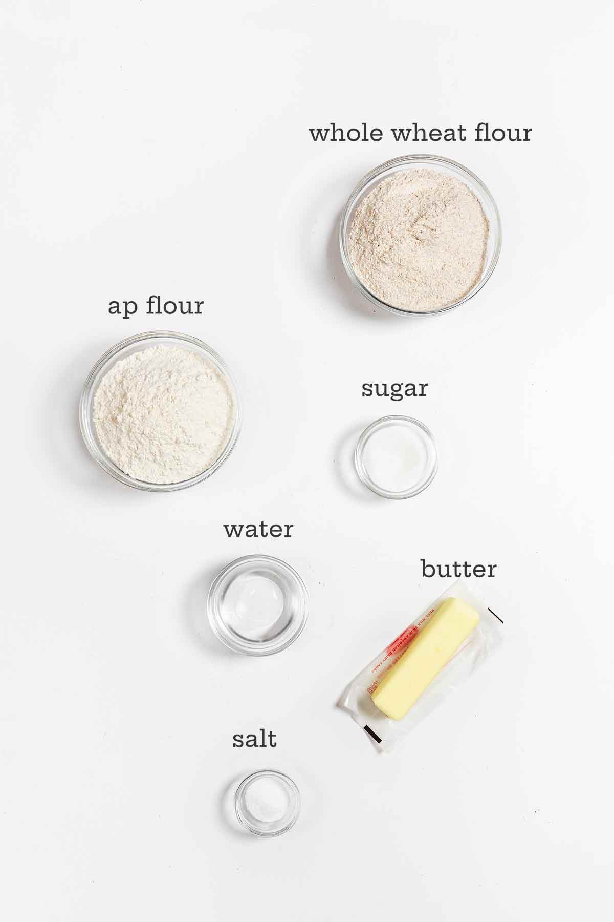Ingredients for whole wheat pie crust--whole wheat flour, all-purpose flour, a stick of butter, water, and sugar.