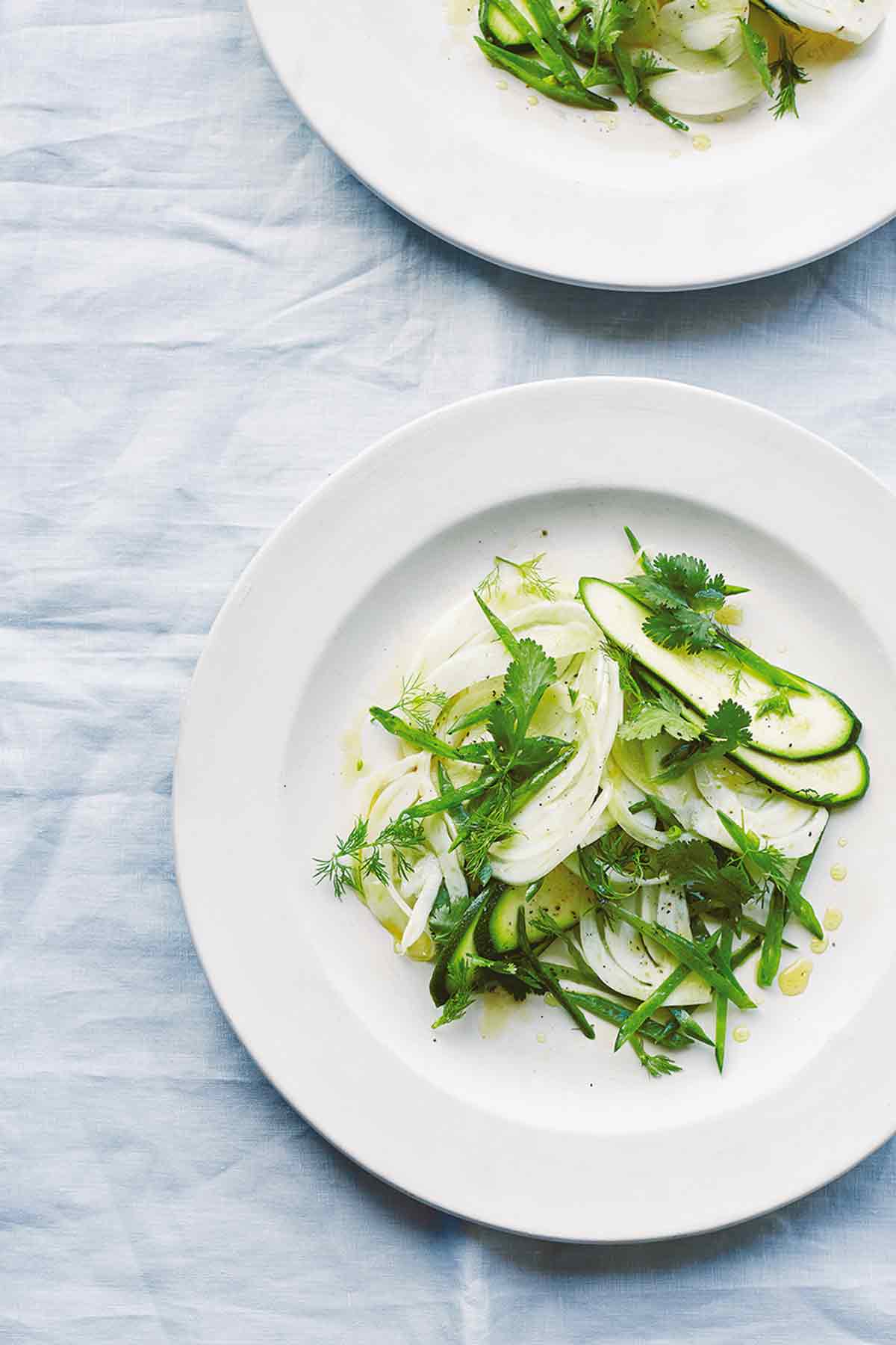 Two white plates topped with zucchini and fennel salad.