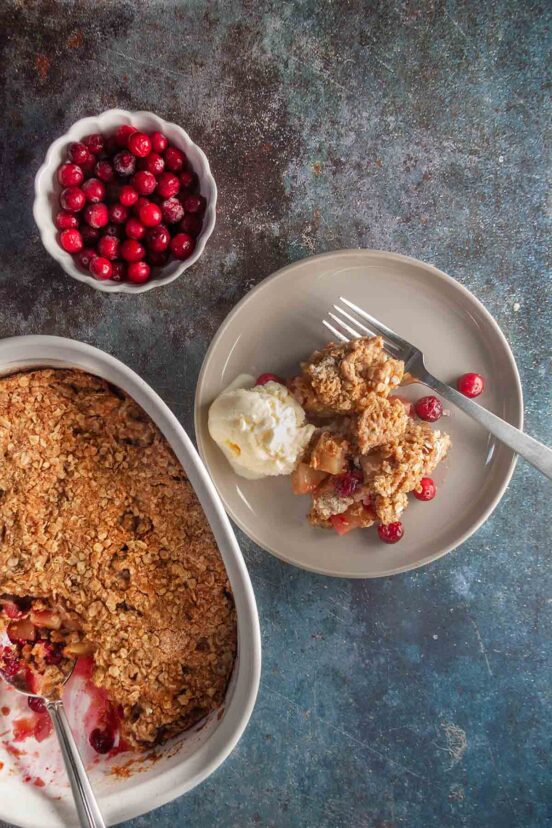 A plate with a serving of cranberry apple crisp and scoop of ice cream.