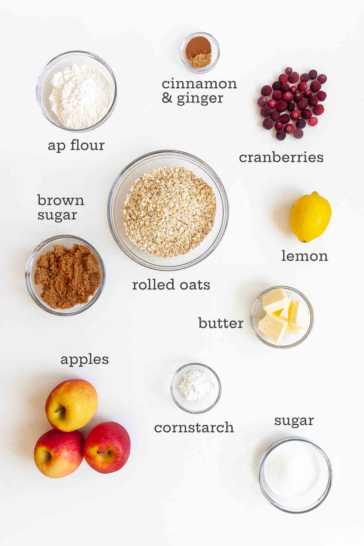 Ingredients for apple cranberry crisp--oats, flour, brown sugar, cranberries, lemon, butter, sugar, cornstarch, and apples.