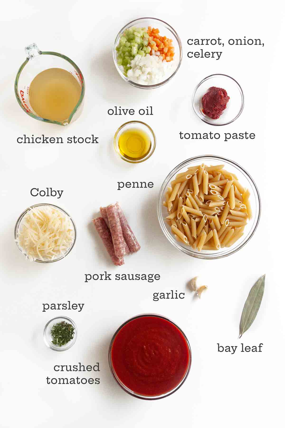 Ingredients for one-pot pasta with sausage meatballs--pasta, vegetables, sausage, stock, crushed tomatoes, tomato past, cheese, garlic, and bay leaf.