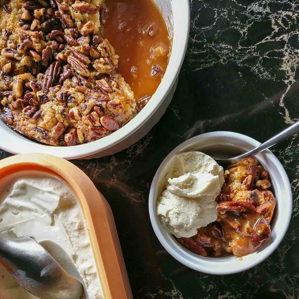 A dish of pecan pie cobbler with a scoop of ice cream on top.