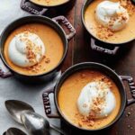 Four small crocks of pumpkin pots de creme--pumpkin pudding topped with crumbled cookie and whipped cream.