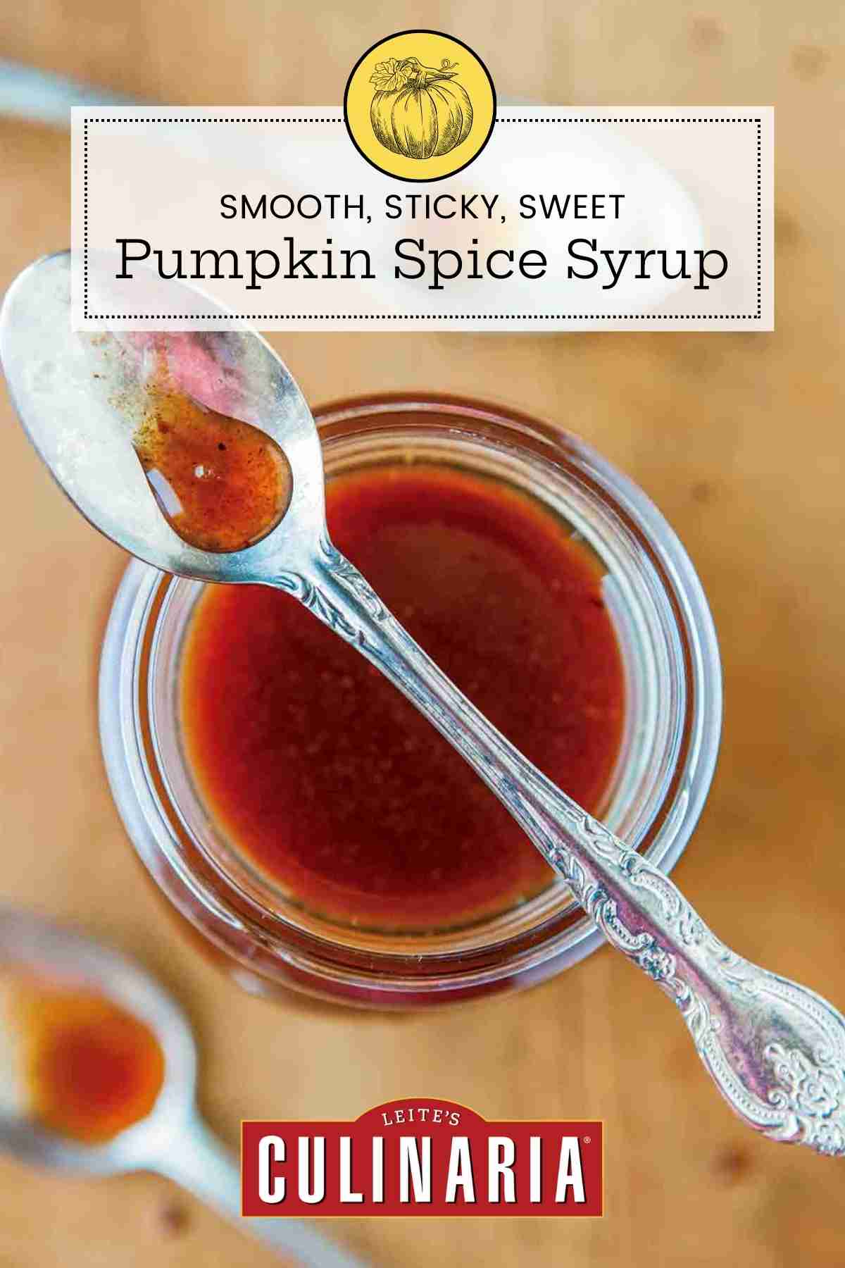 A jar of pumpkin spice syrup with a spoon resting on top and two spoons beside the jar.