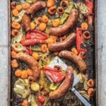 A sheet pan filled with roasted sausages, peppers, and onions.