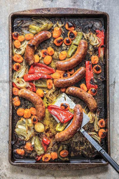 A sheet pan filled with roasted sausages, peppers, and onions.