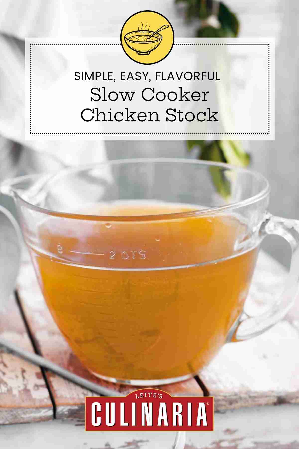 A large measuring cup of slow cooker chicken stock on a wooden table with a ladle on the side.