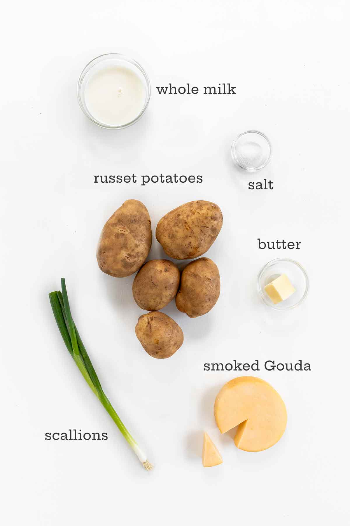 Ingredients for cheesy mashed potatoes--milk, russet potatoes, scallions, butter, salt, and smoked Gouda.