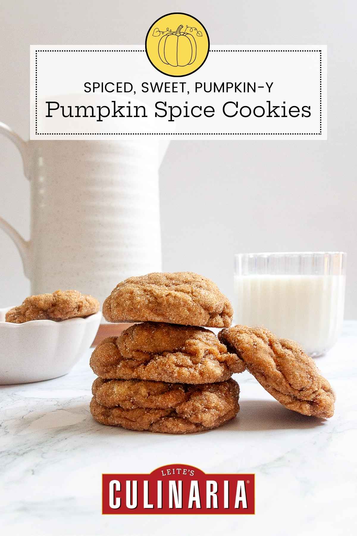 Three pumpkin spice cookies in a stack with another one laying against them with a glass of milk and a pitcher in the background.
