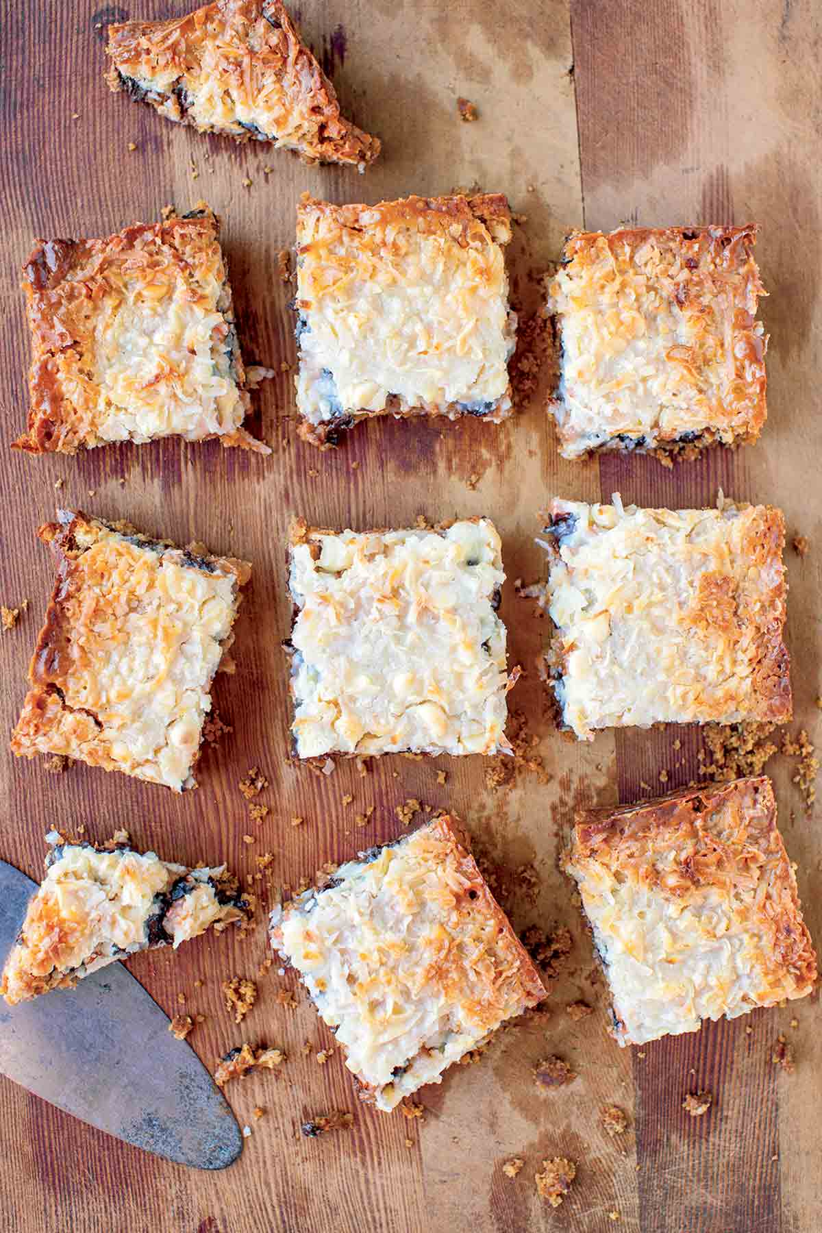 A slab of pumpkin spice seven layer bars cut into ten pieces on a wooden board.