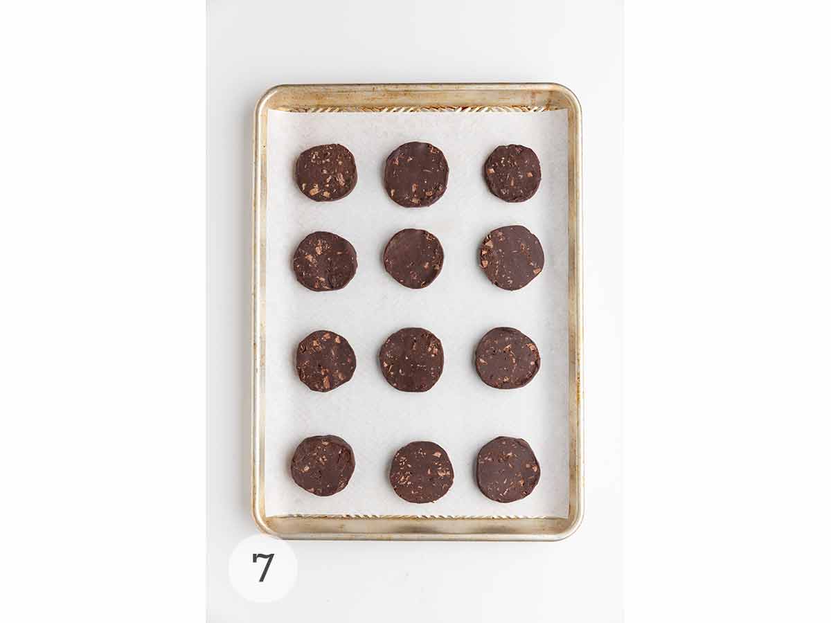 A sheet pan with 12 unbaked chocolate espresso shortbread cookies on it.