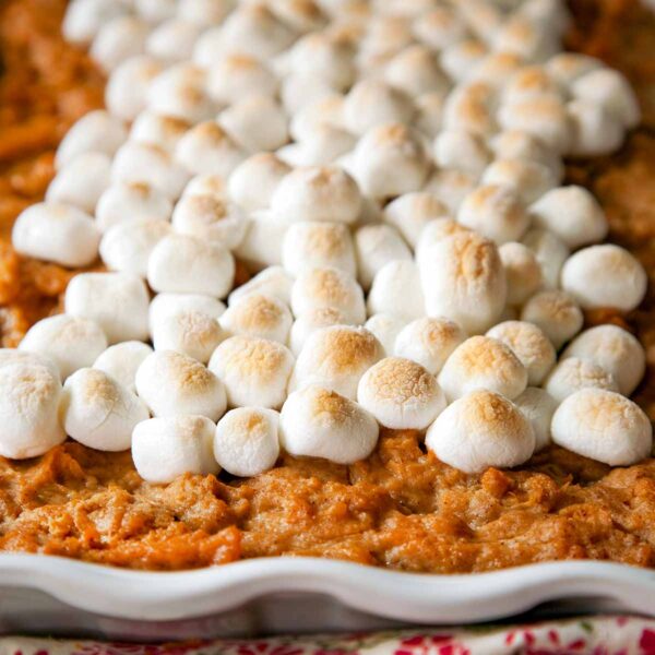 A white dish filled with sweet potato casserole, topped with toasted marshmallows.