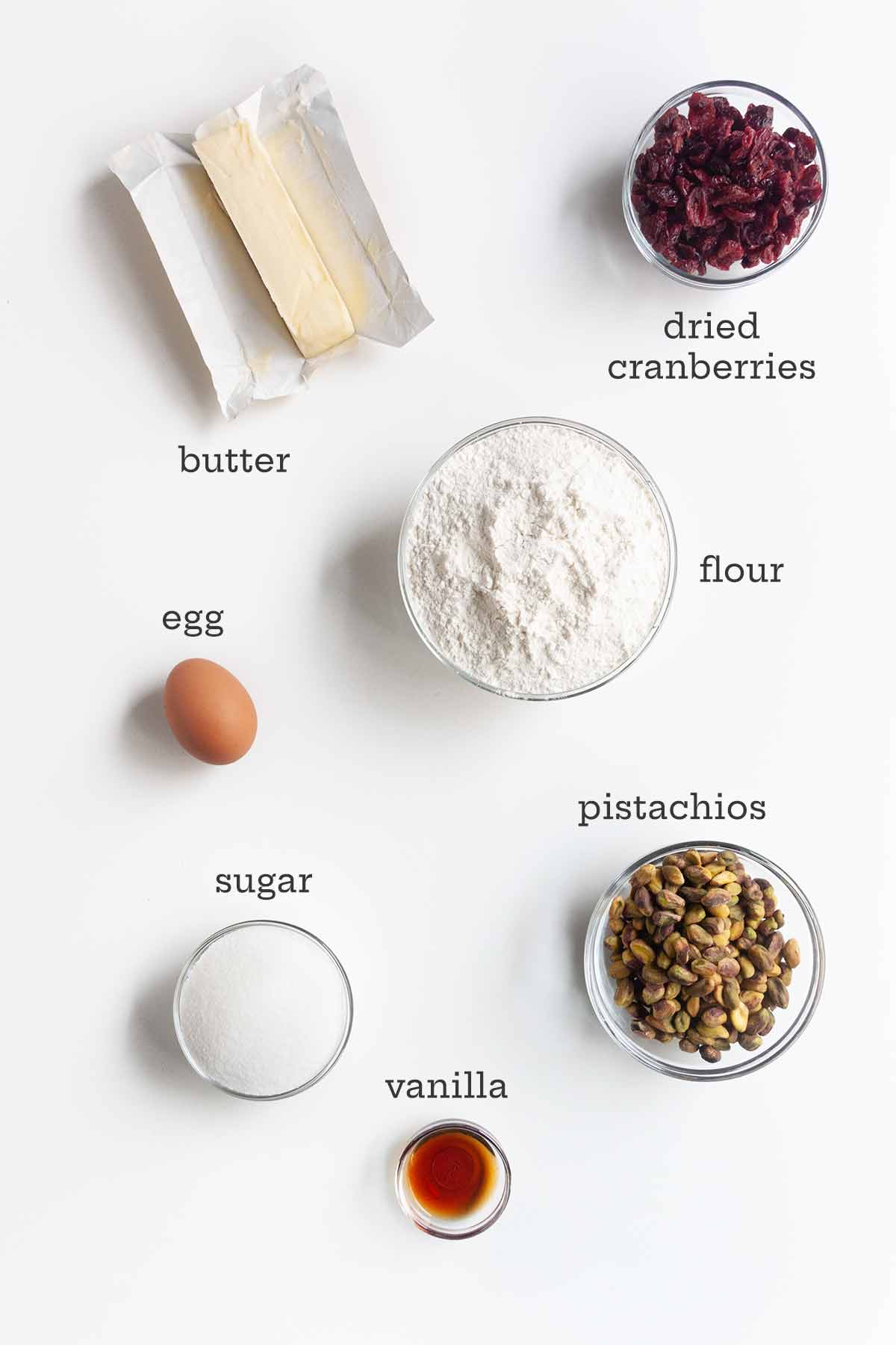 Ingredients for cranberry pistachio cookies--butter, dried cranberries, egg, flour, sugar, pistachios, and vanilla.