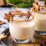 Two eggnogs in glasses with a gingerbread star on the lip and a rim of cinnamon.