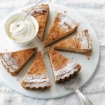 A round white plate with six slices of eggnog pie and a dish of whipped cream.