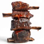 Four grilled short ribs in a stack on a white background.