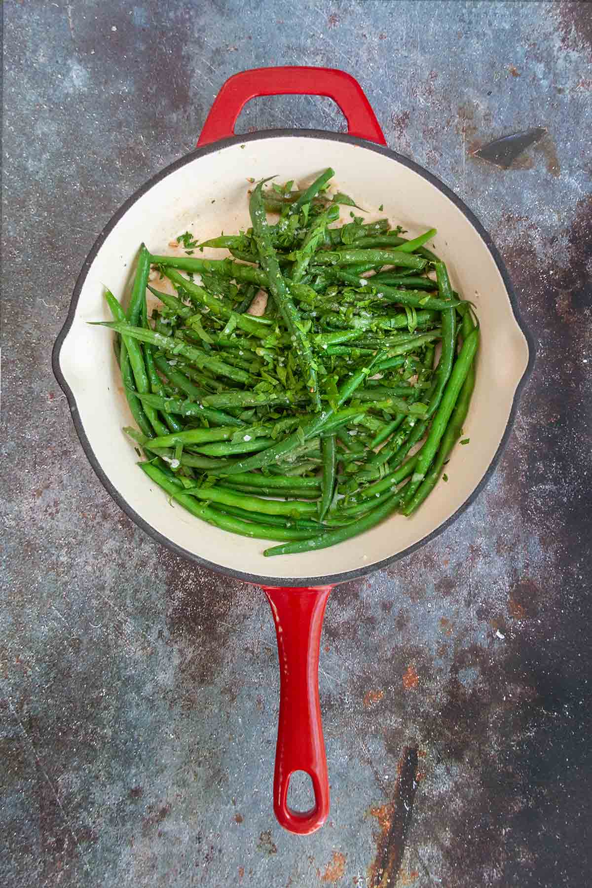 Pan-fried green beans in a red skillet.