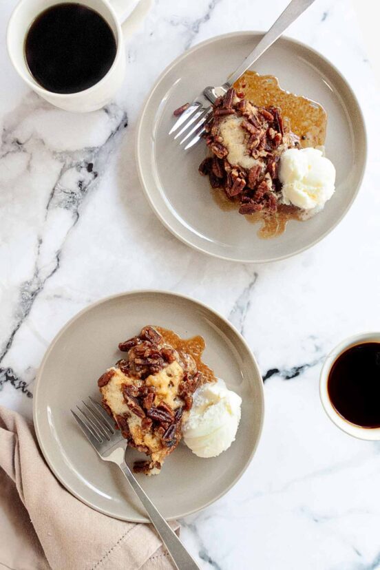 Two plates of pecan pie cobbler with a scoop of ice cream on the side.
