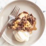 A serving of pecan pie cobbler with a scoop of ice cream and a fork on the side.
