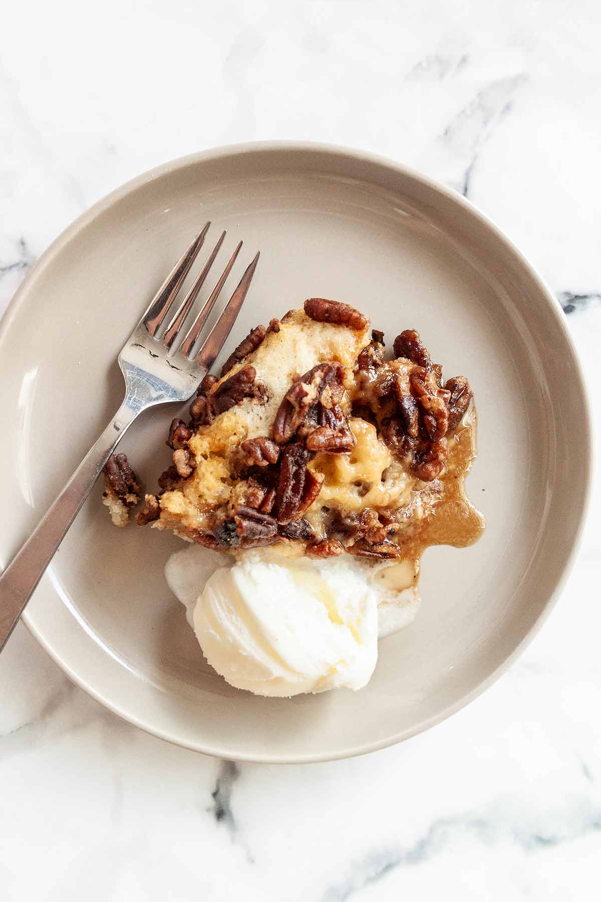 A serving of pecan pie cobbler with a scoop of ice cream and a fork on the side.