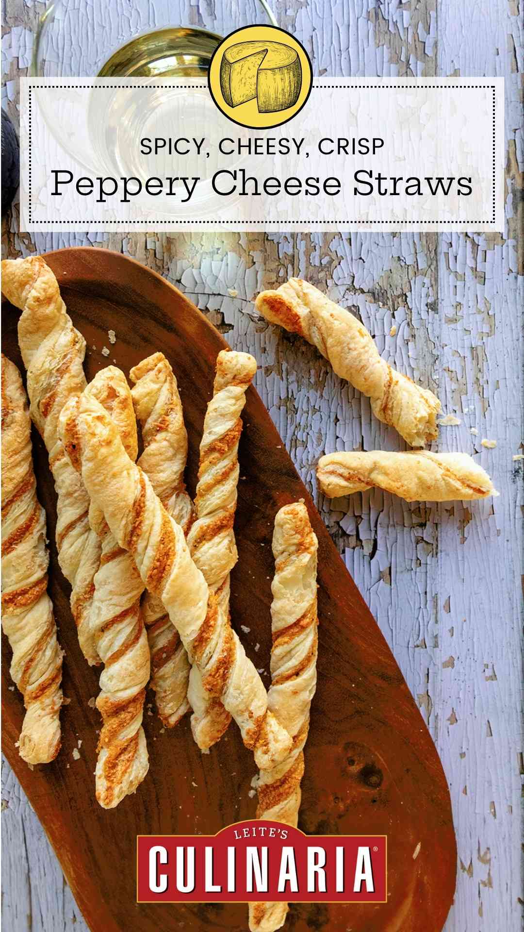 Cheese straws on an oval wooden platter on a distressed wooden surface.
