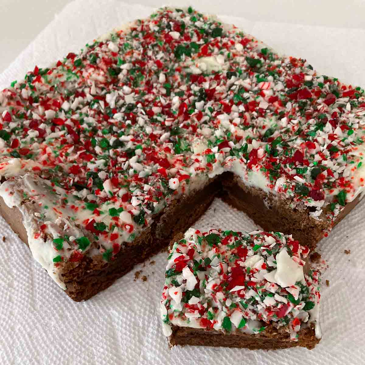 A batch of brownies topped with white frosting and crushed peppermint candies.