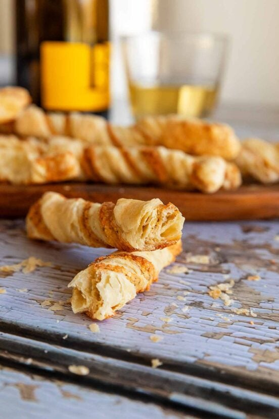 Cheese straws on an oval wooden platter on a distressed wooden surface.