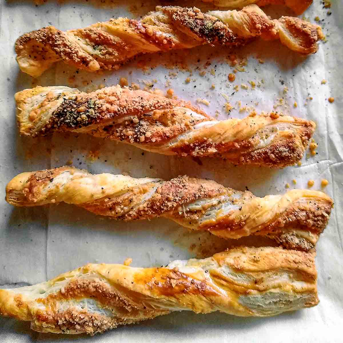 Peppery cheese straws on a sheet of parchment.