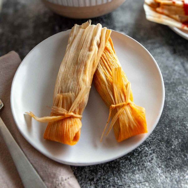 Two tamales on a white plate.