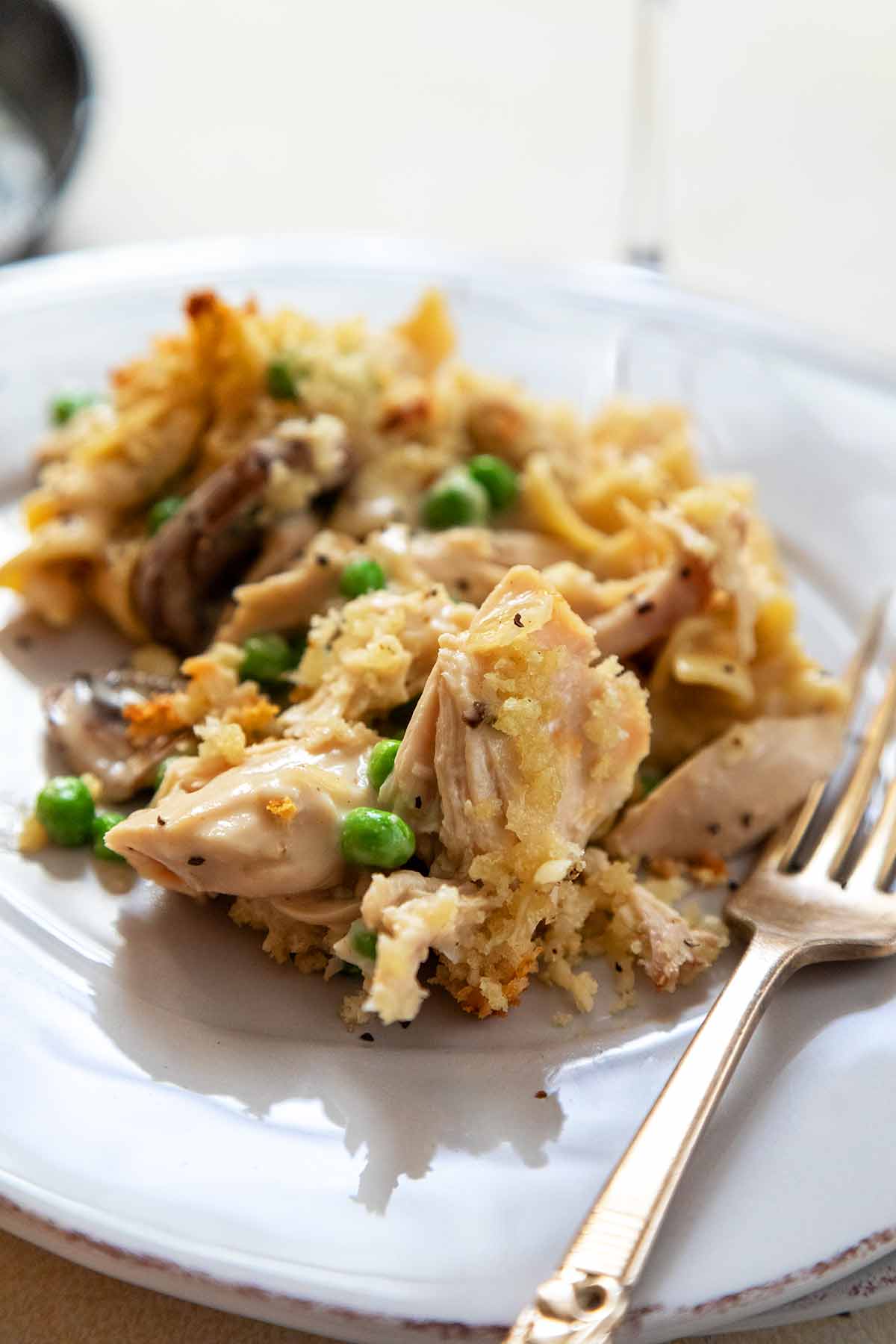 A portion of turkey tetrazzini on a plate with a fork next to it.
