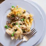 A portion of turkey tetrazzini on a plate with a fork next to it.