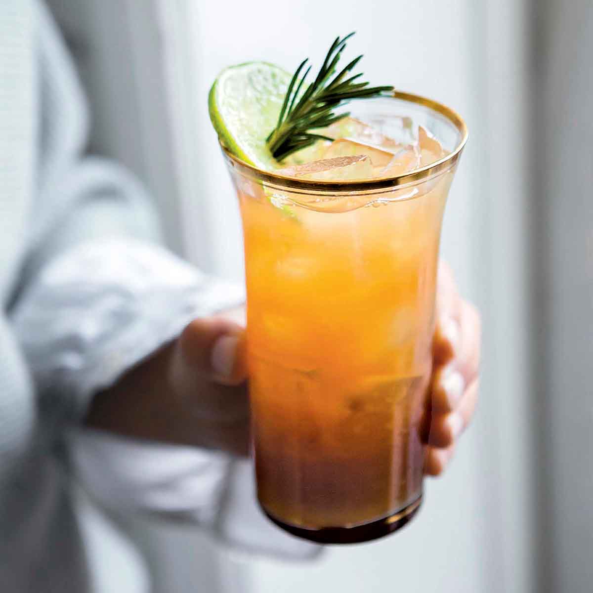 A tall cool glass of a winter mojito made with rum and a sugar syrup of rosemary, thyme, sage leaves.