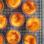 Nine Portuguese coconut custard tarts on a wire rack.