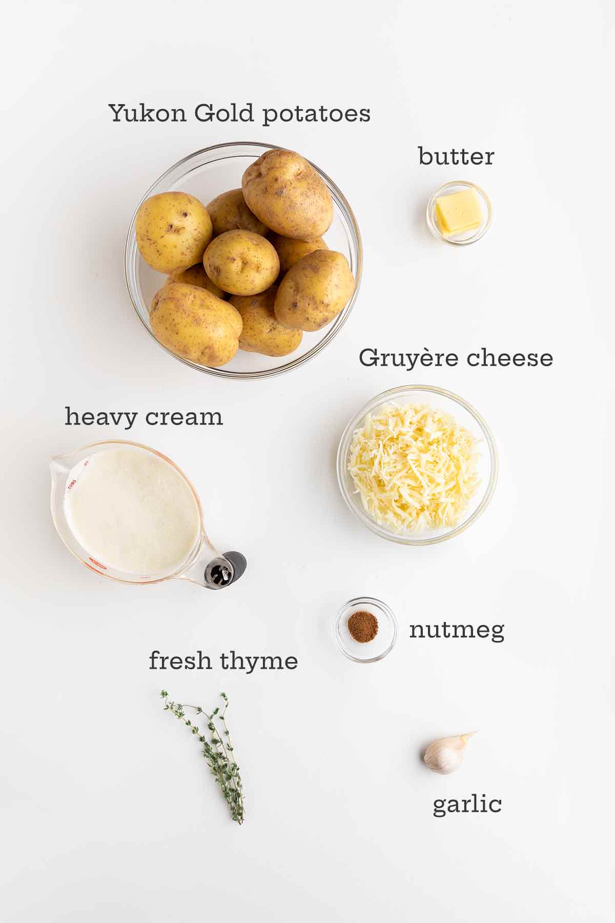 आलू डूफिनोइज़ के लिए सामग्री--आलू, मक्खन, ग्रेयरे, क्रीम, जायफल, अजवायन के फूल, और लहसुन।