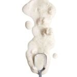 Blue cheese dip, with chunks of blue cheese, spilled in a white background with a spoon.