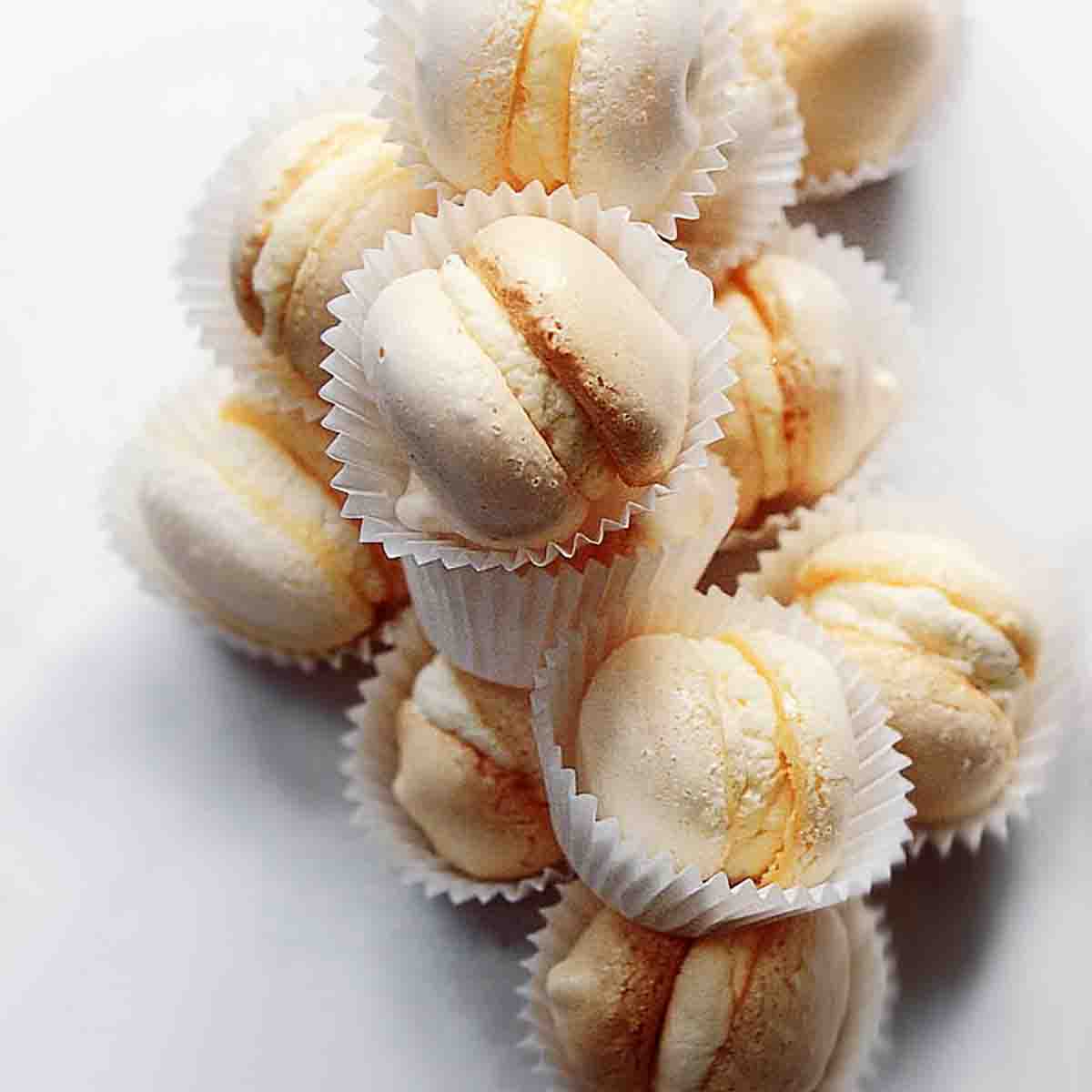A pile of cream-filled macarons, each in a white wrapper.